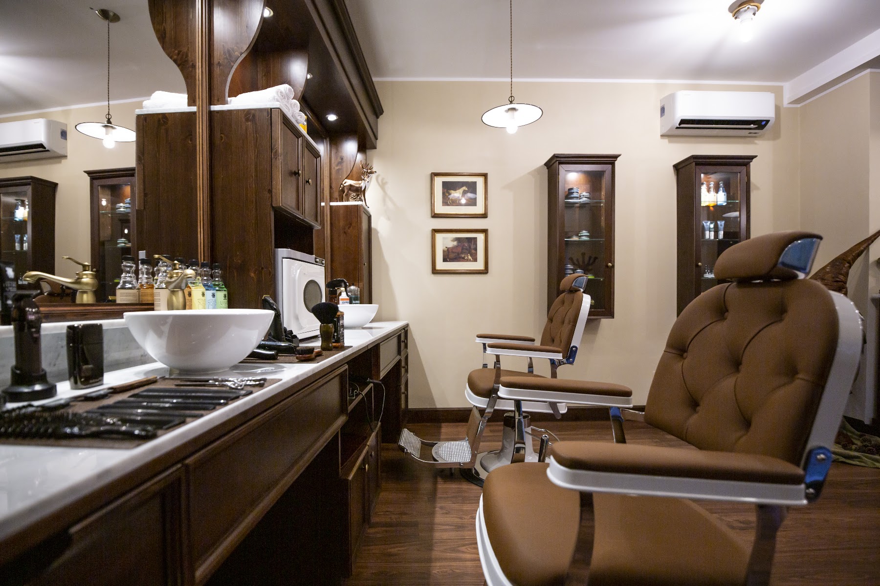 Il salone Clubman: poltrone in pelle cognac, bancone in marmo e boiserie in noce